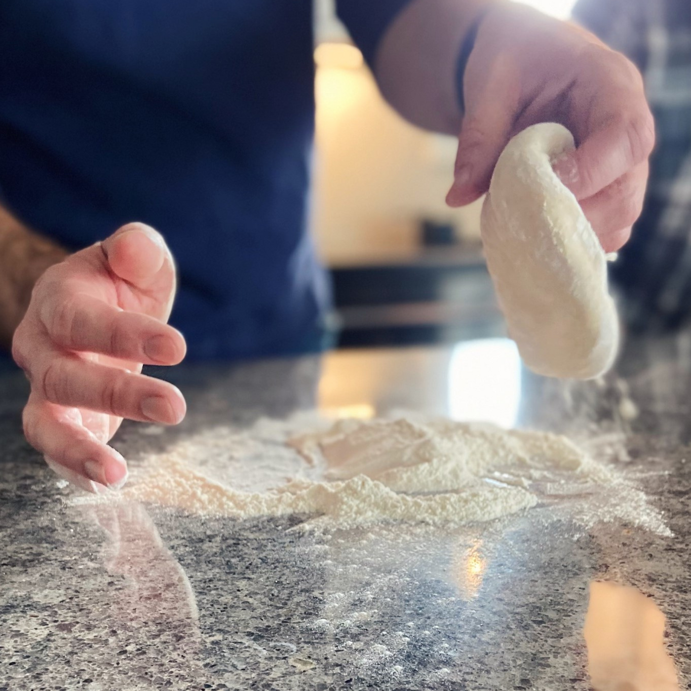 hands working with pizza dough in flour