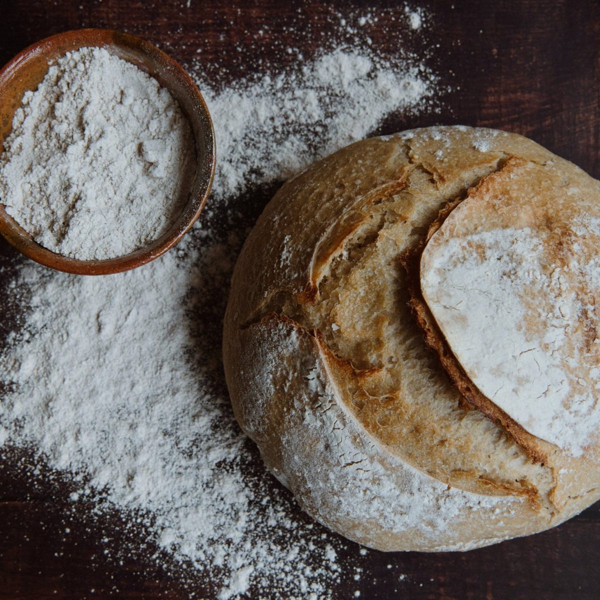 Flour-dusted sourdough boule on dark wood