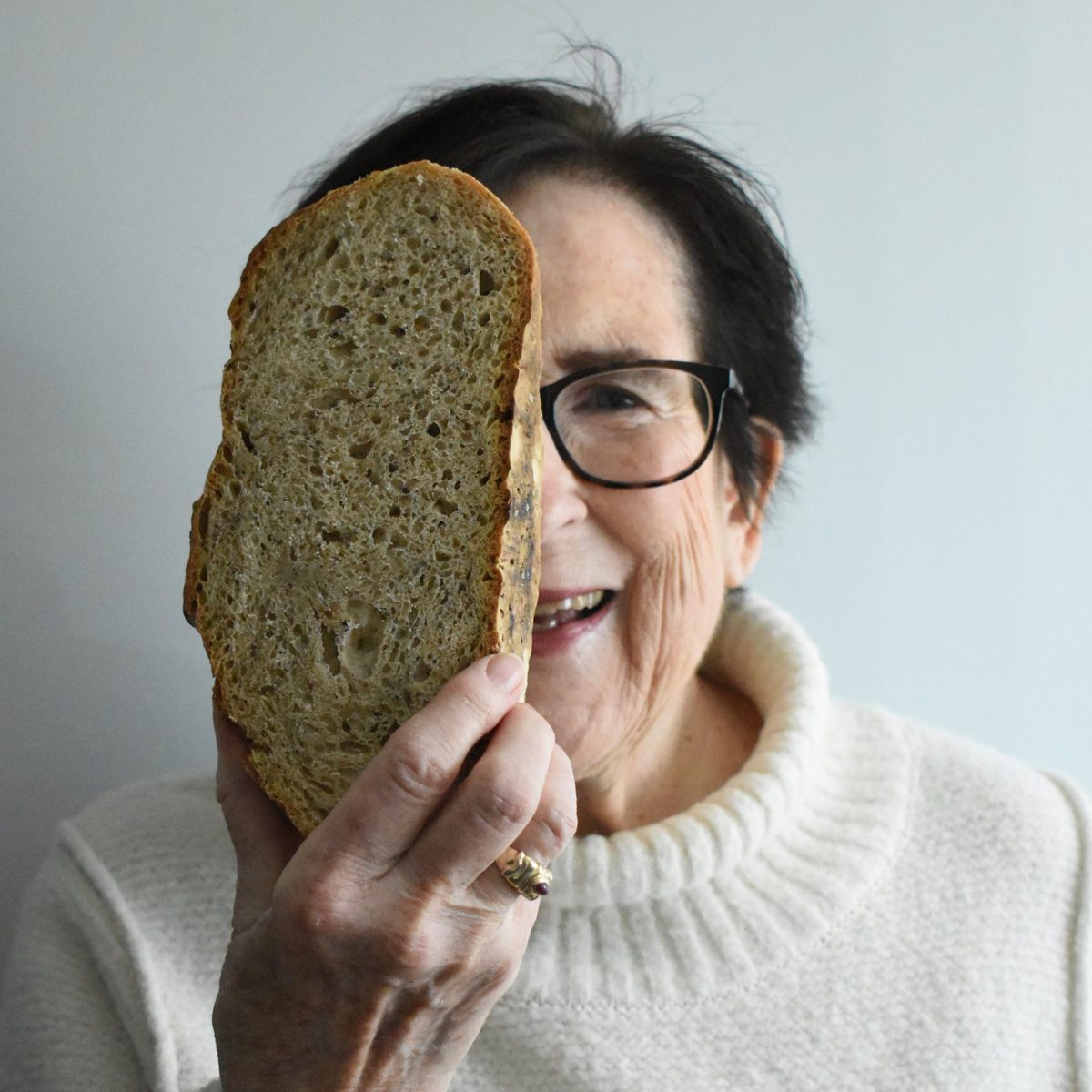 Smiling woman holding a slice of bread up to her face